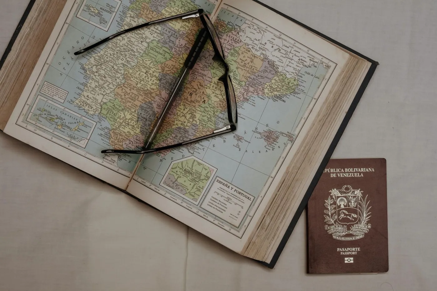 Passport and glasses resting on an open atlas